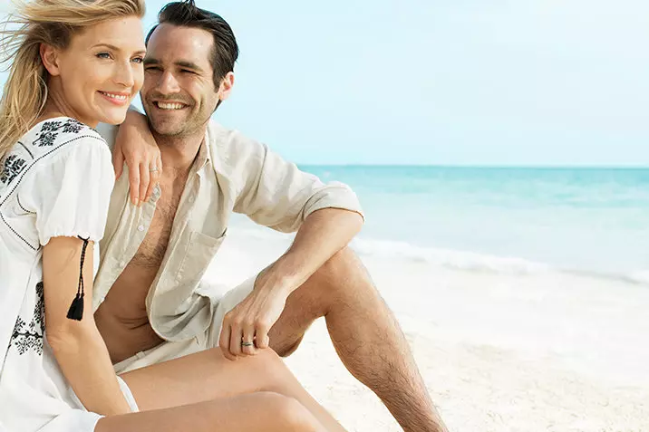 Heureux couple assis sur le sable sur la plage de l'hôtel Beloved Playa Mujeres Mexique