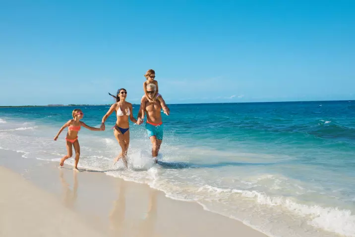 Famille courant sur le rivage de la plage de Playa Mujeres au Mexique