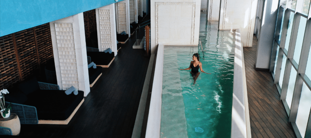 Woman swimming in an indoor pool at a luxury spa in an all-inclusive resort in Mexico, with brick walls and natural light